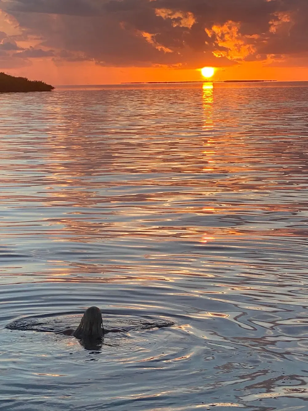 Warm orange sunset over the open ocean with small rolling waves photographed from water level